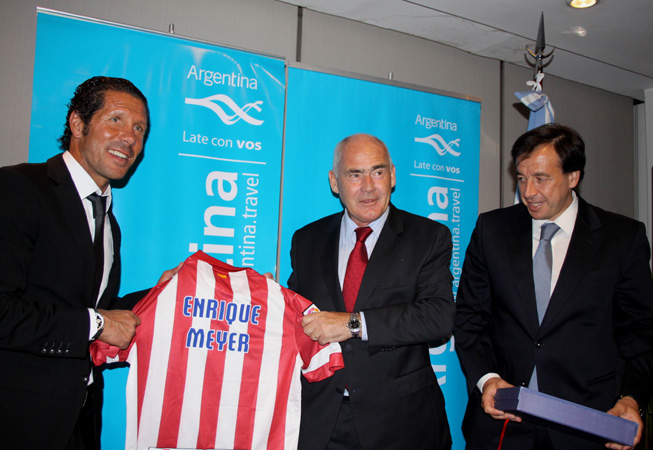 El director Técnico del Atlético Madrid, Diego Simeone, entrega la camiseta del club al ministro de Turismo de la Nación, Enrique Meyer, junto al vicepresidente de la institución española, Antonio Alonso.